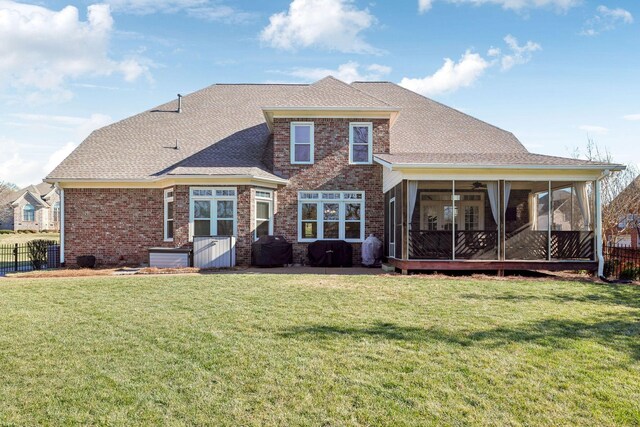 rear view of house featuring a sunroom, fence, a lawn, and roof with shingles