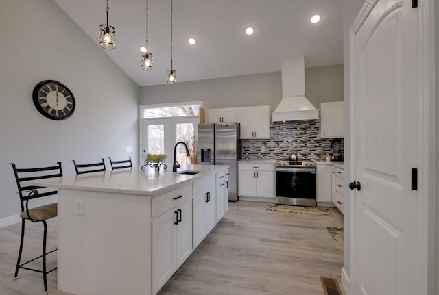 kitchen with premium range hood, a sink, visible vents, a kitchen breakfast bar, and appliances with stainless steel finishes