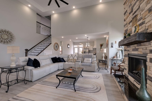 living area featuring a high ceiling, light wood finished floors, a fireplace, and stairway