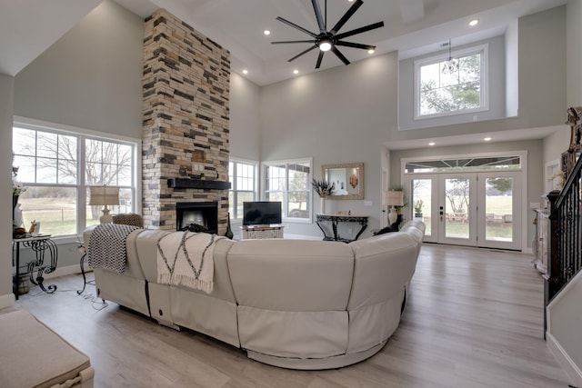 living room with light wood-type flooring, a fireplace, a wealth of natural light, and baseboards