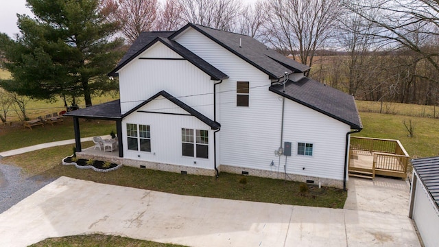 view of side of home featuring a shingled roof, crawl space, a patio area, and a deck