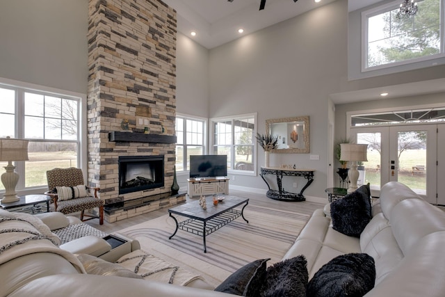 living area with french doors, a stone fireplace, and a towering ceiling