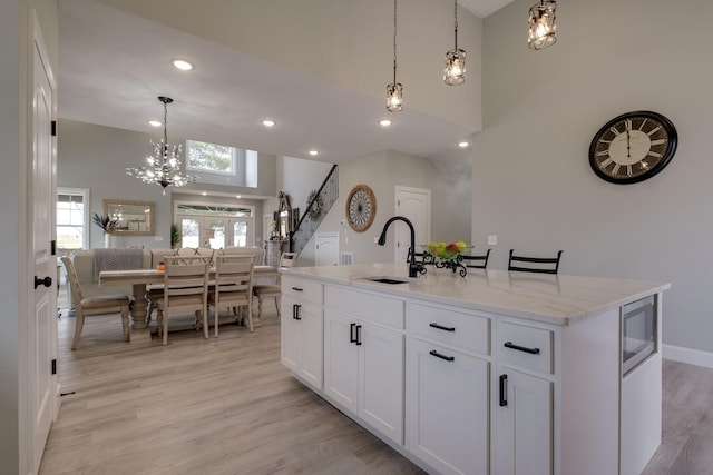 kitchen with a healthy amount of sunlight, light wood-style floors, stainless steel microwave, and a sink