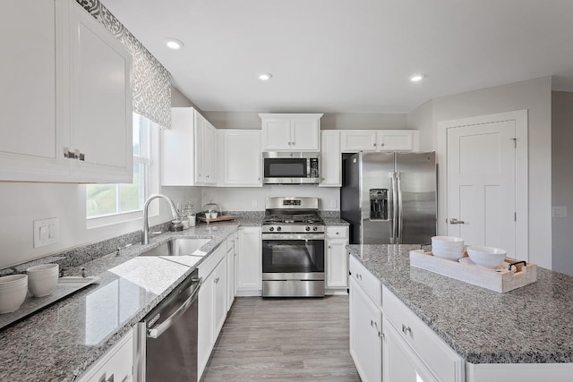 kitchen featuring appliances with stainless steel finishes, stone counters, white cabinetry, and a sink