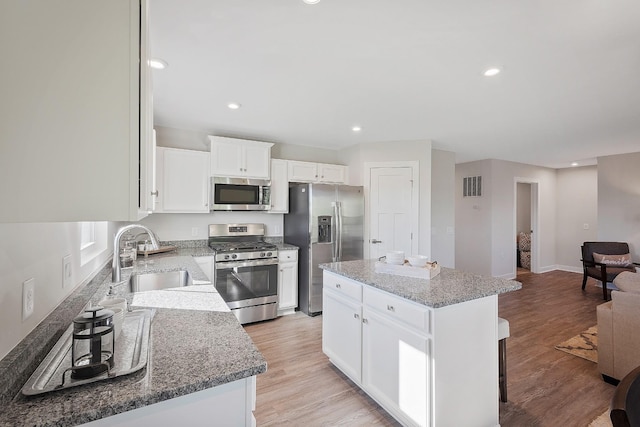 kitchen featuring light wood-style flooring, appliances with stainless steel finishes, a sink, and a center island