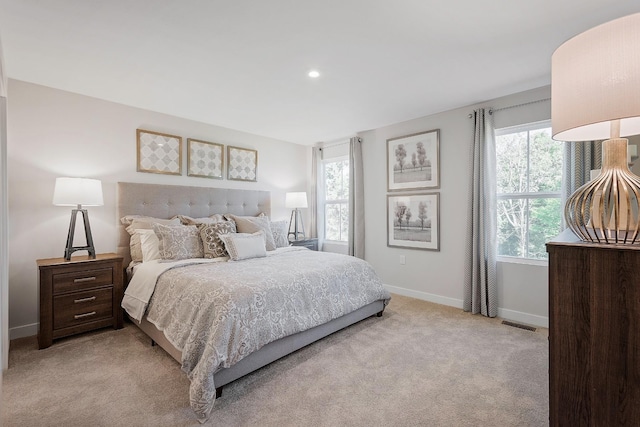 bedroom with light colored carpet, visible vents, baseboards, and multiple windows