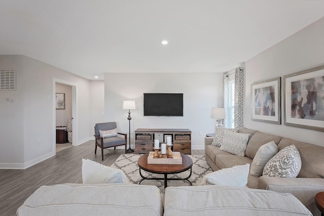 living area featuring baseboards, visible vents, wood finished floors, and recessed lighting