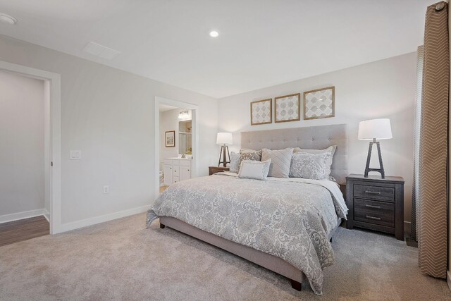 carpeted bedroom with ensuite bath and baseboards