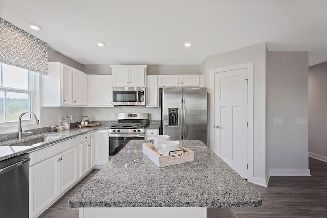 kitchen featuring a sink, white cabinetry, baseboards, appliances with stainless steel finishes, and light stone countertops