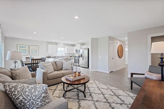 living area featuring light wood finished floors, baseboards, and recessed lighting