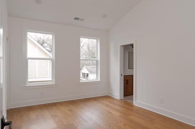 unfurnished room with vaulted ceiling, baseboards, visible vents, and light wood-style floors