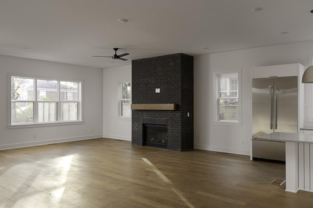 unfurnished living room featuring a fireplace, baseboards, and wood finished floors