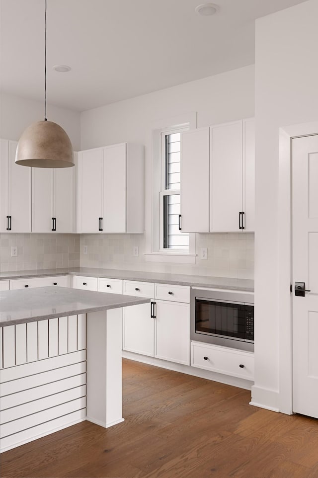 kitchen with white cabinetry, tasteful backsplash, light countertops, and wood finished floors