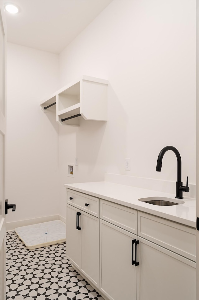 clothes washing area with light floors, washer hookup, a sink, and cabinet space