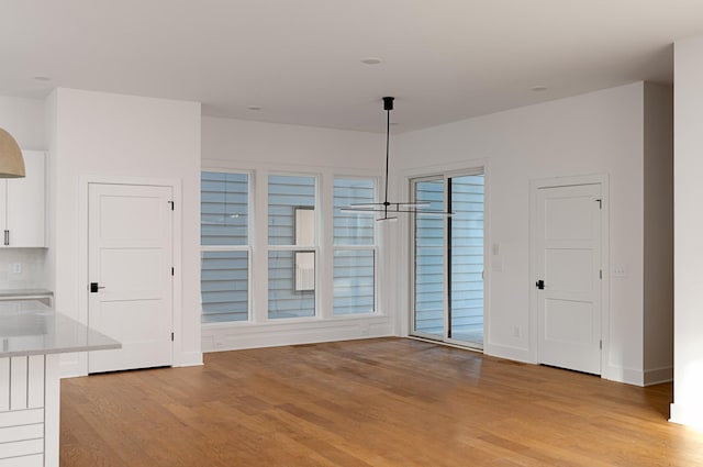 unfurnished dining area featuring baseboards and light wood finished floors