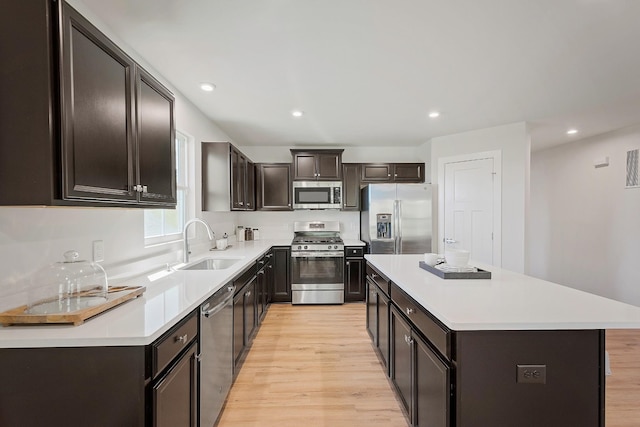 kitchen with stainless steel appliances, light wood-type flooring, a center island, and light countertops