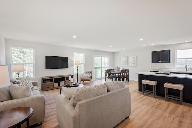 living area featuring light wood-style floors, baseboards, a wealth of natural light, and recessed lighting