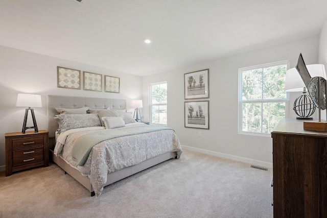 bedroom featuring baseboards, multiple windows, visible vents, and light colored carpet