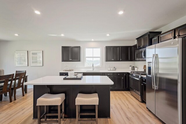 kitchen featuring appliances with stainless steel finishes, a breakfast bar, a center island, and light wood finished floors