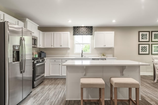 kitchen featuring light countertops, appliances with stainless steel finishes, light wood-style floors, white cabinetry, and a sink