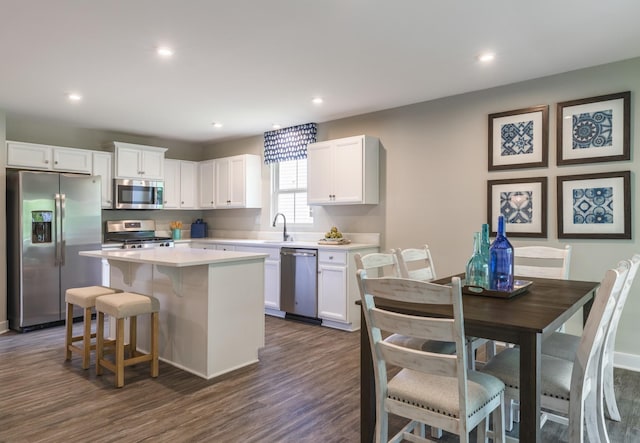 kitchen with a kitchen island, appliances with stainless steel finishes, white cabinets, and a sink