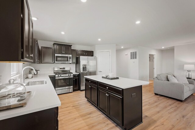 kitchen featuring a sink, light countertops, appliances with stainless steel finishes, light wood-type flooring, and a center island