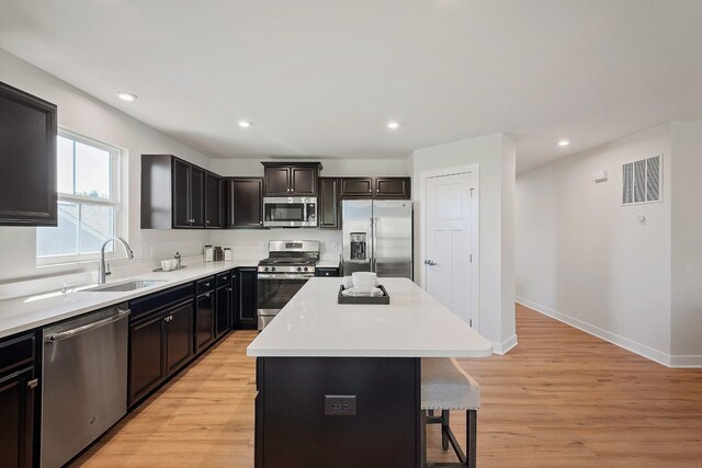 kitchen with stainless steel appliances, a breakfast bar, a kitchen island, a sink, and visible vents