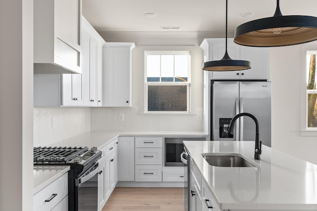 kitchen featuring a healthy amount of sunlight, appliances with stainless steel finishes, light countertops, and a sink