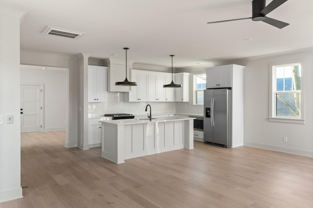 kitchen featuring visible vents, decorative backsplash, light countertops, stainless steel refrigerator with ice dispenser, and a sink