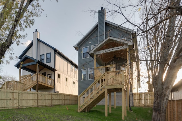 rear view of property with a fenced backyard, a chimney, stairway, and a lawn