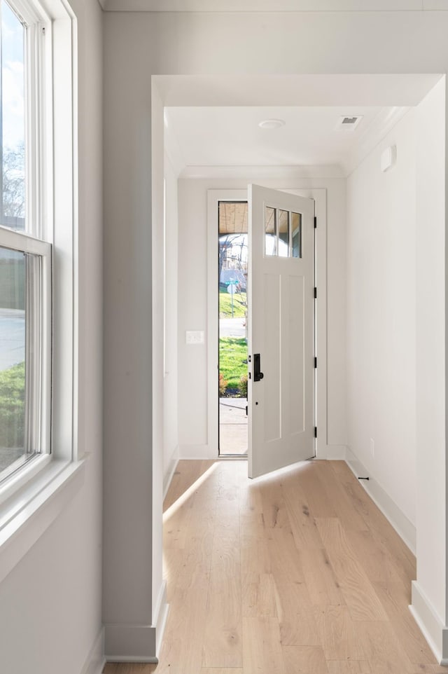 entrance foyer with light wood-style floors, crown molding, and baseboards