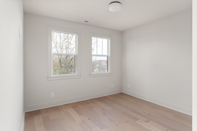 unfurnished room featuring light wood-type flooring, visible vents, and baseboards