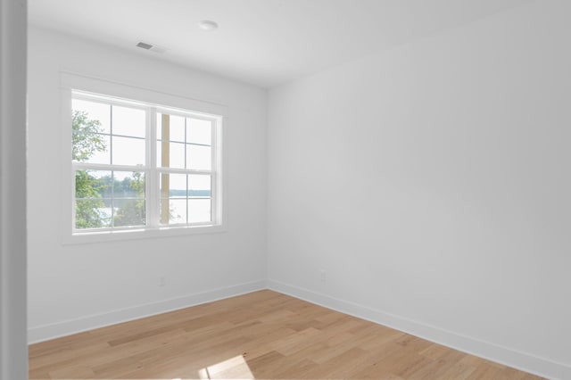 spare room with visible vents, light wood-style flooring, and baseboards