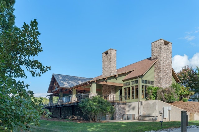 back of property featuring a yard, a chimney, and central AC unit