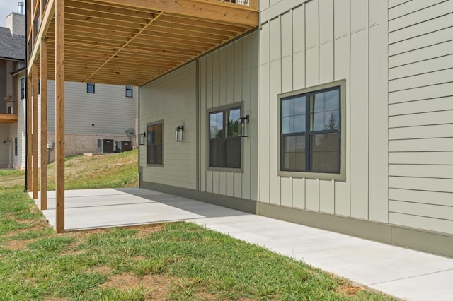 view of home's exterior with board and batten siding, a yard, central AC, and a patio