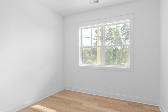 empty room with light wood-type flooring, visible vents, and baseboards