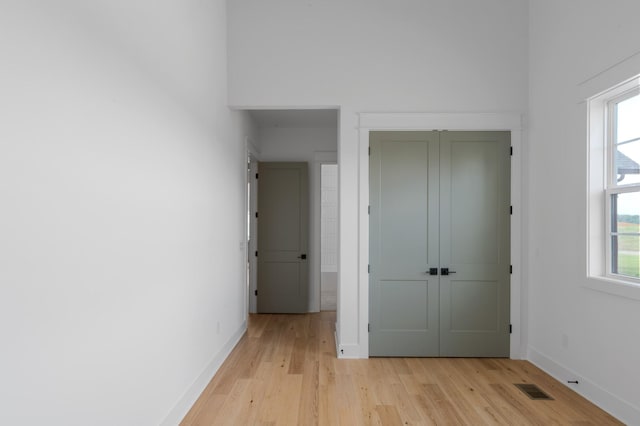 unfurnished bedroom with light wood-type flooring, baseboards, visible vents, and a closet