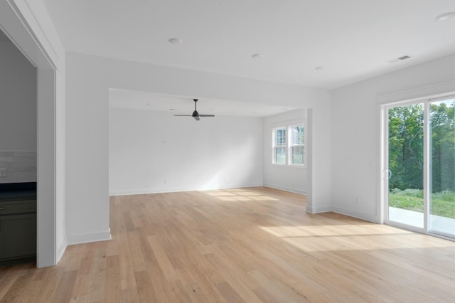 unfurnished living room featuring light wood-style flooring, a ceiling fan, visible vents, and baseboards