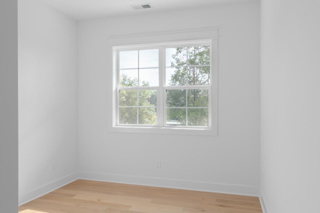 empty room featuring light wood-type flooring, visible vents, and baseboards