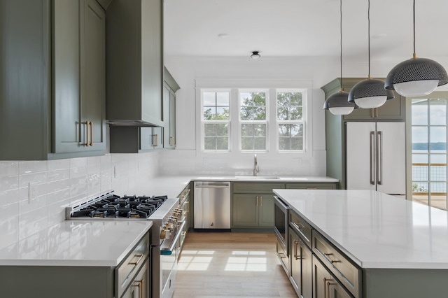 kitchen featuring light countertops, a sink, high quality appliances, and decorative backsplash