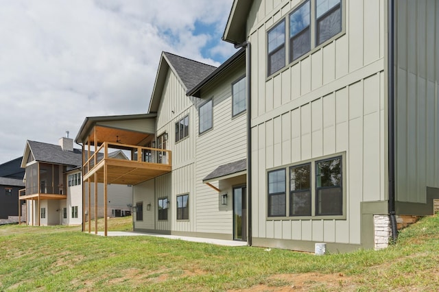 back of house featuring board and batten siding, central AC, a yard, and a balcony