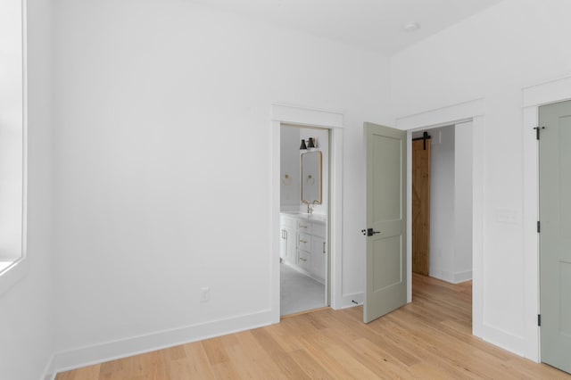 unfurnished bedroom with light wood-type flooring, a sink, and baseboards