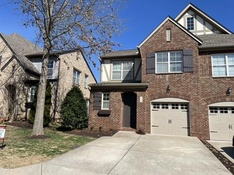 traditional-style house featuring driveway, brick siding, and an attached garage