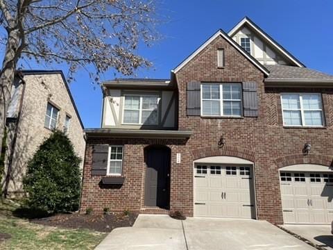 view of front of home featuring driveway, a garage, and brick siding