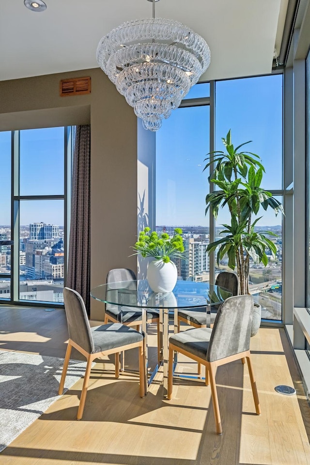 dining room featuring a view of city, a wall of windows, and a notable chandelier