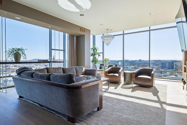 living room with a healthy amount of sunlight, an inviting chandelier, floor to ceiling windows, and wood finished floors