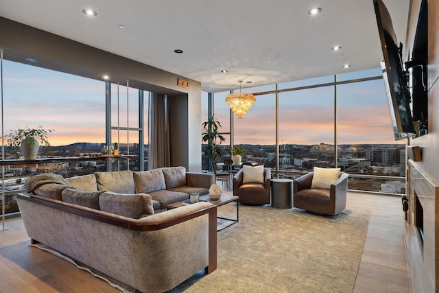 living room featuring recessed lighting, floor to ceiling windows, an inviting chandelier, and wood finished floors