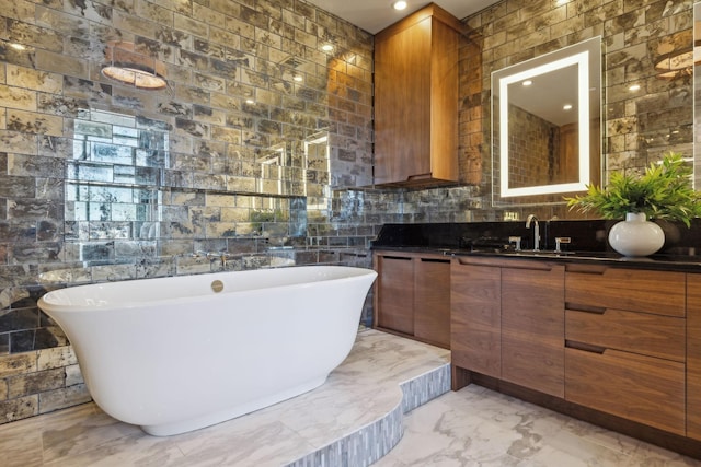 bathroom with marble finish floor, a freestanding bath, and vanity