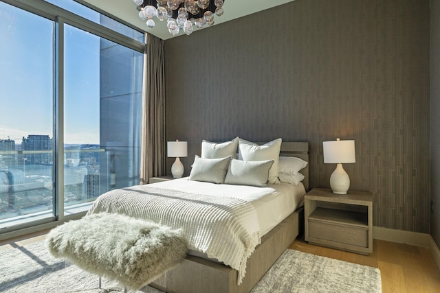 bedroom featuring baseboards, a city view, an inviting chandelier, and wood finished floors