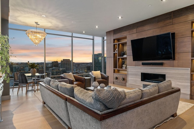 living area featuring light wood-style flooring, recessed lighting, expansive windows, a tiled fireplace, and an inviting chandelier